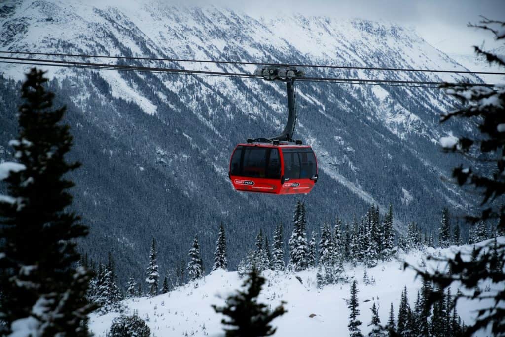 A red gondola suspended above snowy Whistler mountains, capturing the unique origin for shipping goods, equipment, and vehicles internationally.