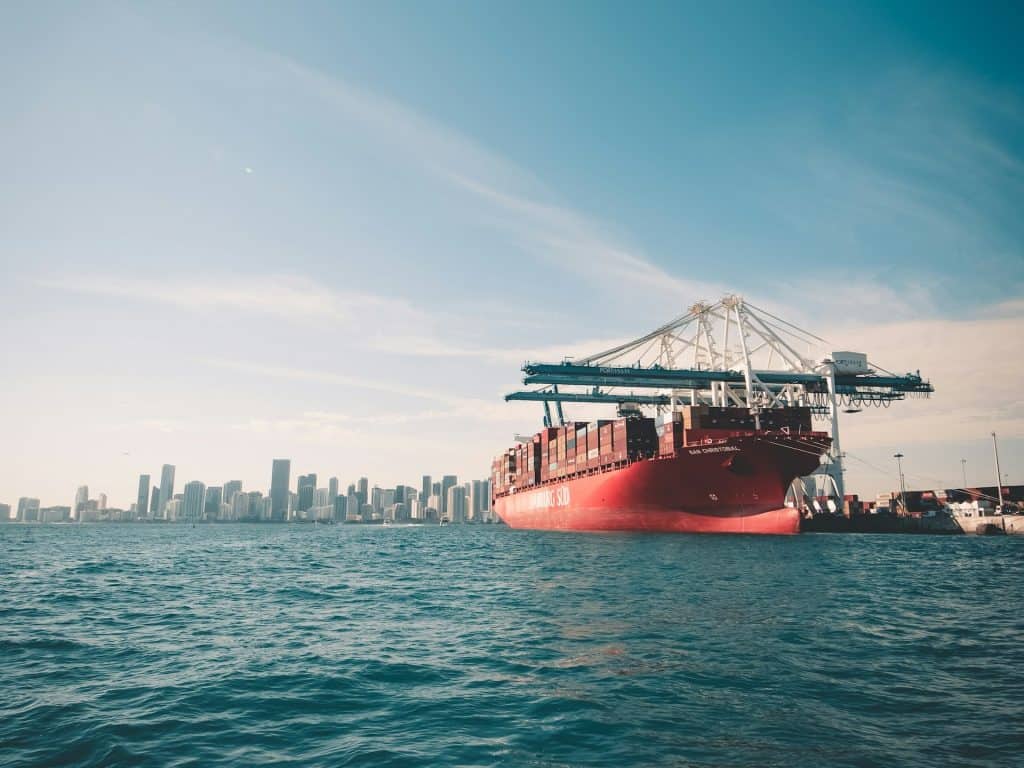 A vibrant cargo ship docked at a bustling port, highlighting the essential role of freight forwarders in managing global shipping and logistics.