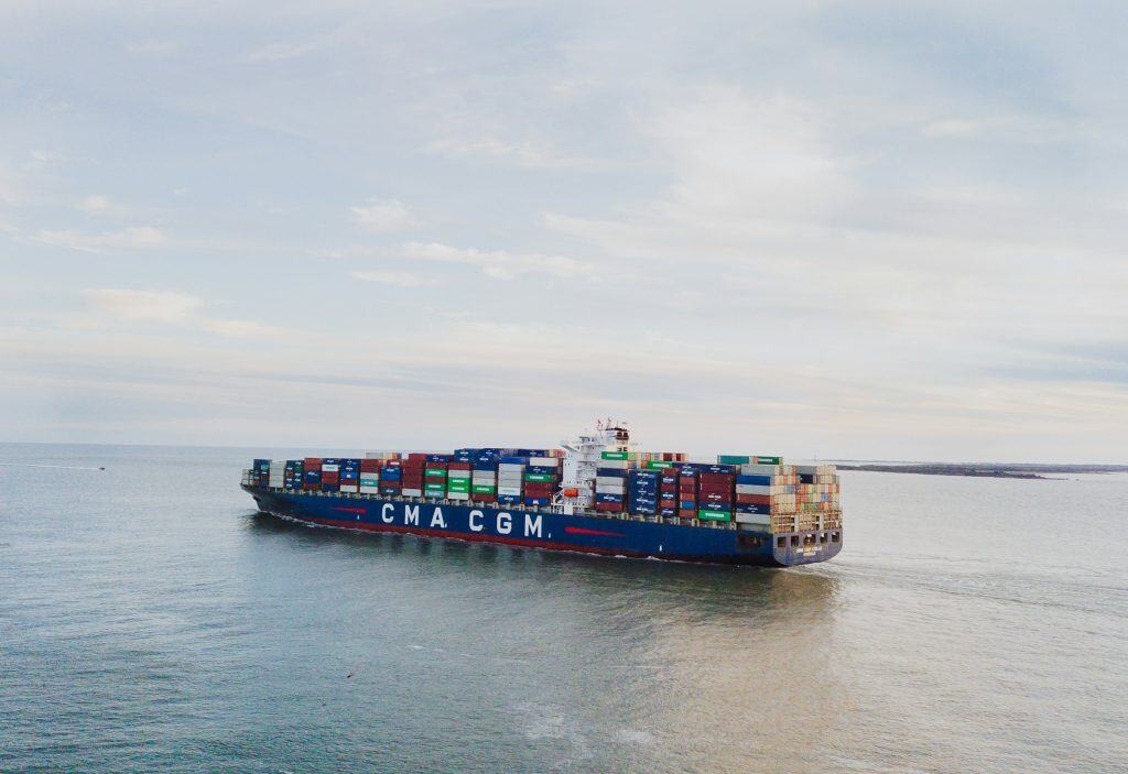 A large CMA CGM container ship navigating open waters, showing the impact of major shipping route changes on international shipping disruptions.